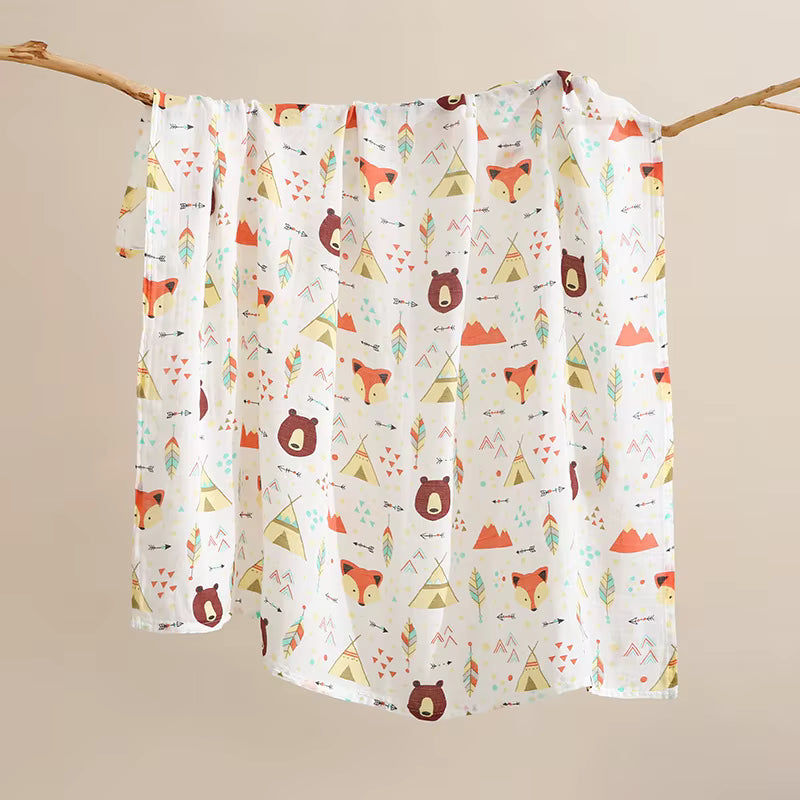 Baby blanket with forest animal pattern hanging on a branch against a beige background